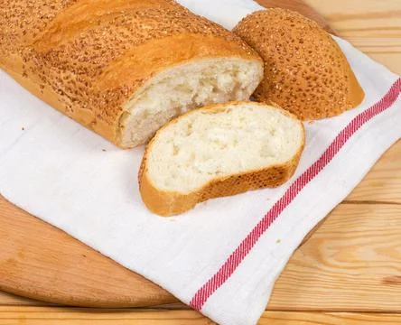 Partly cut wheat bread sprinkled with sesame on napkin Stock Photos