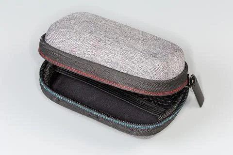 Partly open small plastic case with zipper on gray background Stock Photos