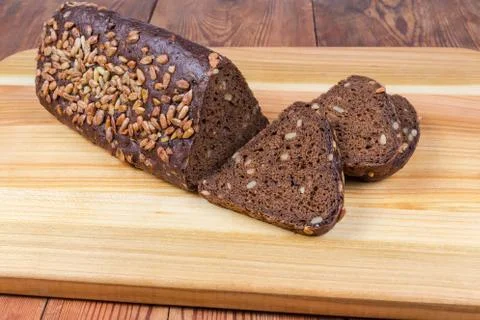 Partly sliced brown bread triangular shape on cutting board closeup 스톡 사진