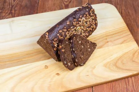Partly sliced brown bread triangular shape on cutting board closeup 스톡 사진