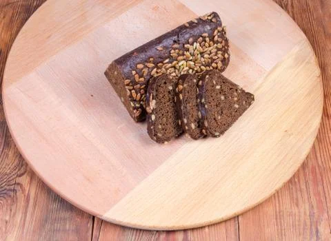 Partly sliced brown bread triangular shape on wooden serving board Foto stock