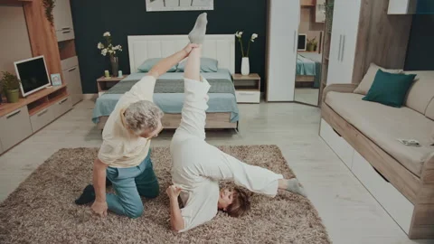 Partner-assisted supine leg raise, yoga-inspired floor exercise 库存影片 327540005