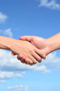 Partner hand between a man and a woman on blue sky background, teamwork Stock-Fotos