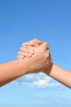 Partner hand between a man and a woman on blue sky background, teamwork 스톡 사진