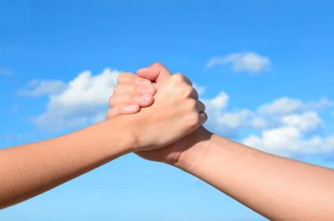 Partner hand between a man and a woman on blue sky background, teamwork Stock Photos