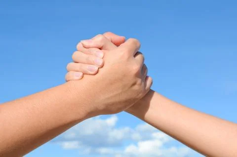 Partner hand between a man and a woman on blue sky background, teamwork Stock-Fotos