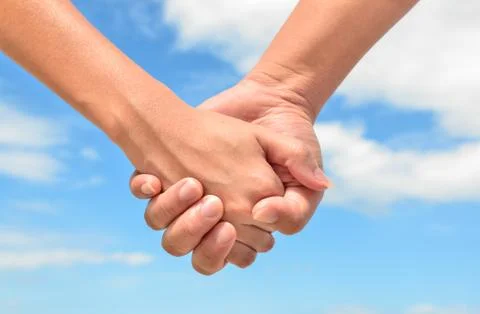 Partner hand between a man and a woman on blue sky background, Teamwork 스톡 사진
