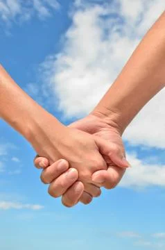 Partner hand between a man and a woman on blue sky background Stock Photos