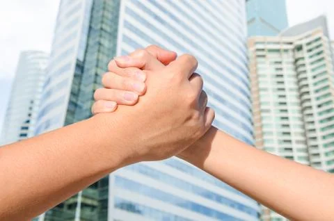 Partner hand between a man and a woman on building background Stock Photos