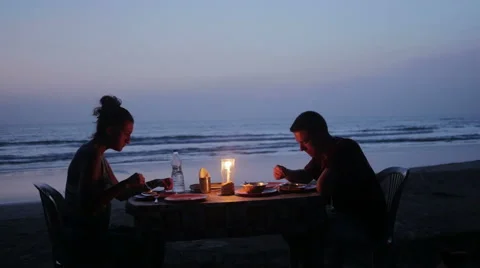 Partners eating dinner with candle on beach Stock Footage 61085301