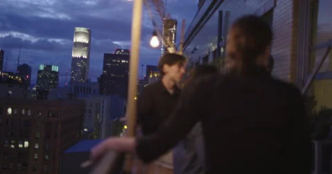 Party guests in soft focus with Downtown Los Angeles skyline behind them 4K Stock Footage 63447754