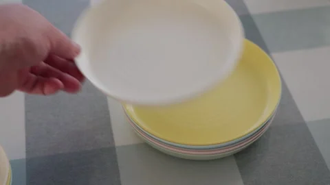 Party Prep Underway as Hand Stacks Colorful Plastic Plates with a Light Clack Stock Footage 320808901