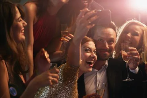 Party time. Cropped shot of a young group of friends taking selfies in a Stock Photos