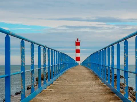 Pass to the lighthouse on the stone walkway between the safety ramps Stock Photos