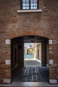 Pass through an archway with a view of the river and ancient buildings. Stock Photos