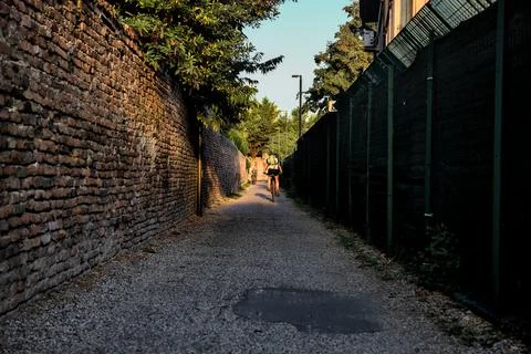 Passageway next to a brick wall and a fence in a park at sunset Fotos de archivo