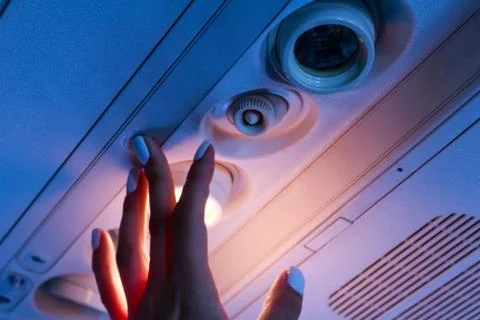 The passanger hand closeup turn on the light in the airplane Stock Photos