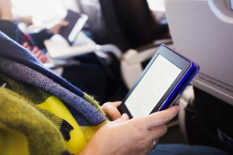 A passenger on an aircraft using a digital tablet. Stock Photos
