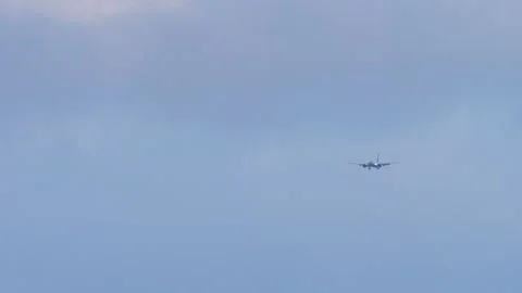 Passenger airplane approaching with landing lights in overcast sky Stock Footage 346977919