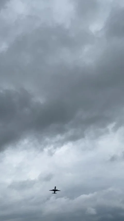 Passenger airplane flies overhead beneath heavy gray storm clouds, creating.. Stock Footage 341738579
