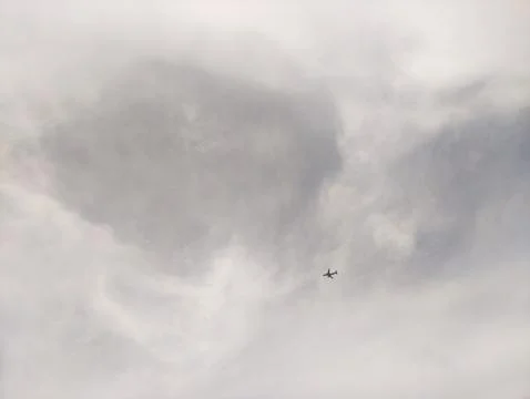Passenger airplane flying through a cloudy sky on an overcast day Stock Photos