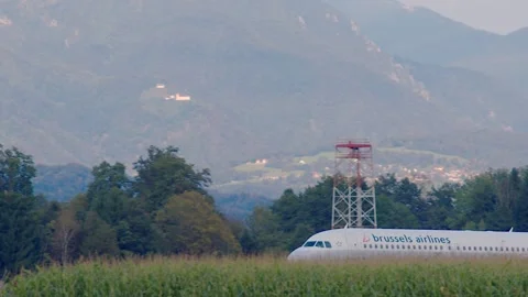 Passenger airplane landing behind the corn field at Ljubljana Airport, Slovenia Stock Footage 163533307