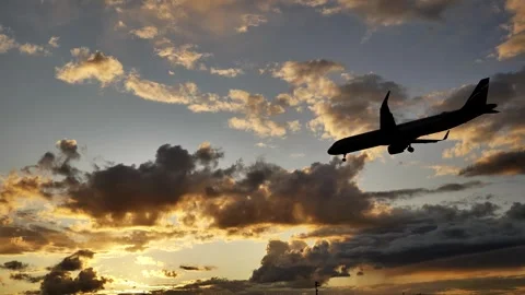 Passenger airplane landing at sunset in cloudy sky Stock Footage 315745375