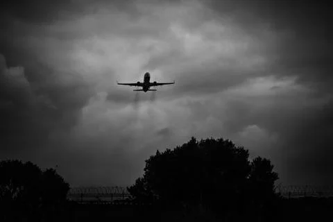 Passenger airplane taking off in a dark cloudy day. Low key image to have a d Stock Photos