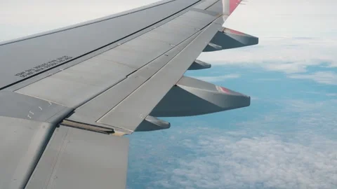 Passenger airplane wing flying over thick white clouds under blue sky, aerial 動画素材 334704966