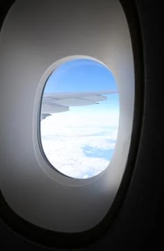 Passenger airplane wing visible through the window during the flight above .. Stock Photos