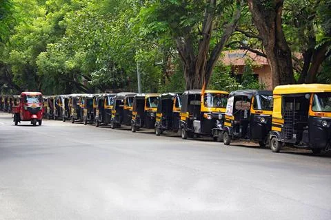 Passenger auto Rickshaws standing in queue on road while Red coloured Riks... Stock Photos