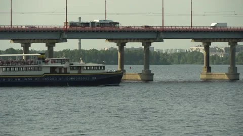 A passenger boat floats down the river. In the background is a road bridge. Vidéo 159757725