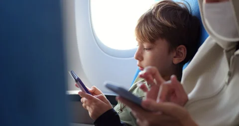 Passenger boy focused on his e-book, reading during flight Video stock 303993306