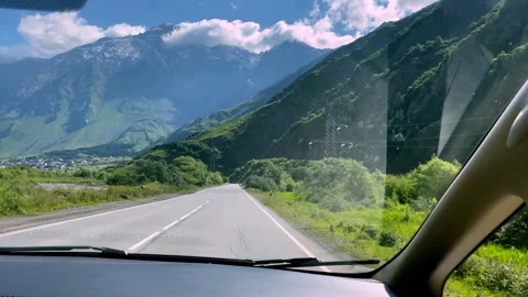 A passenger car drives through a mountainous area during the day. Stock Footage 248971983