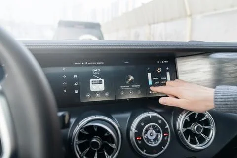 The passenger controls the temperature in the car interior with his finger by Stock Photos