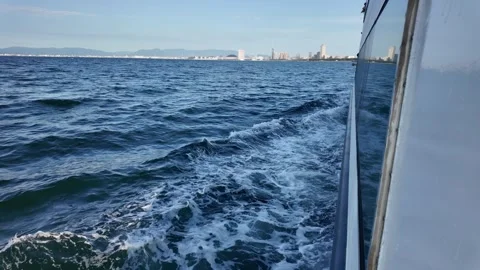 A passenger ferry looking out at the deep blue ocean with a distant city skyline 스톡 동영상 337277287