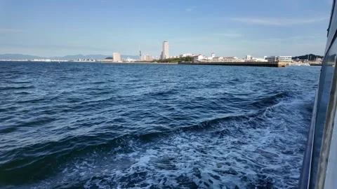 A passenger ferry looking out at the deep blue ocean with a distant city skyline Vídeos de archivo 337277295