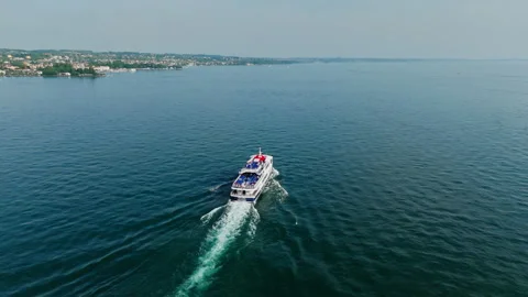 Passenger ferry navigating open lake surface near Garda shoreline Stock Footage 340067316