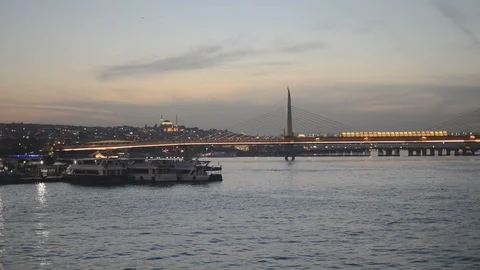 A passenger ferry sails across the frame with Haliç bridge in the background Stock Footage 91079953