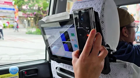 Passenger hand tapping smartphone for contactless mobile payment on taxi rear Stock Footage 325958811