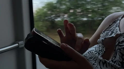 Passenger hands tapping smartphone in case beside window during travel, with Видео 344587829