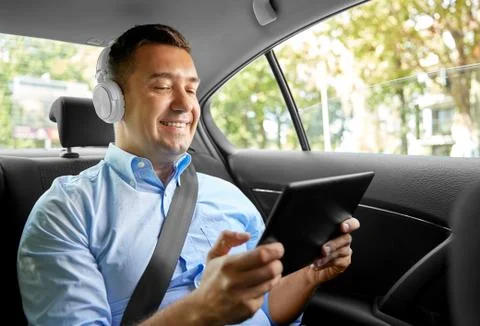 Passenger with headphones using tablet pc in car Stock Photos