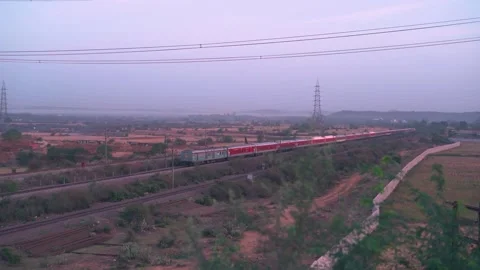 A Passenger Indian railways Train passing by a village in rural India Stock Footage 275801477