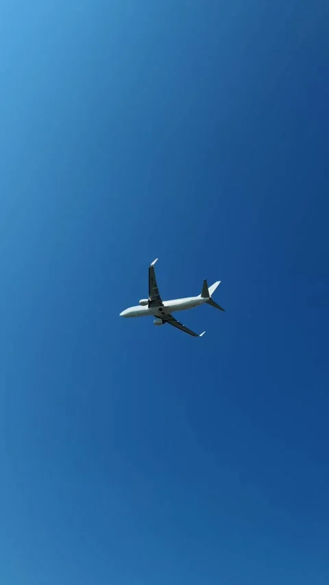 Passenger jet flies overhead against a deep blue sky and white clouds. Stock Footage 346561129