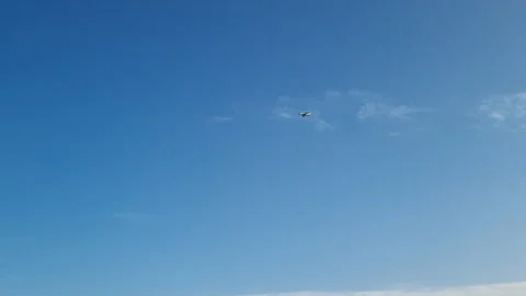 Passenger jet flying high, cutting through azure sky, leaving crisp white Stock Footage 315064152