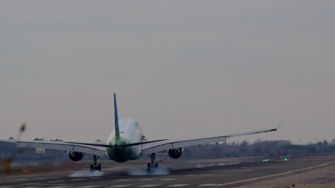 Passenger jet landing, lowering wheels, descending toward runway, touching down Stock Footage 306697820