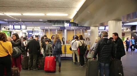 Passenger linedup at the information desk inside Amsterdam train station Stock Footage 46154574