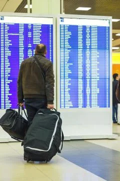 Passenger looking at blue timetable board Stock Photos
