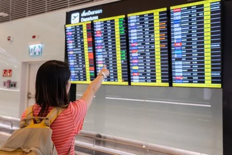 Passenger Looking at Flight Schedule in Terminal Area of Airport Stock Photos