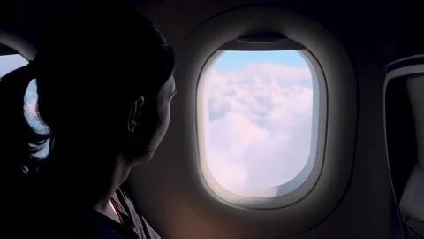 Passenger looking through airplane window at clouds during descent before Stock Footage 339281375